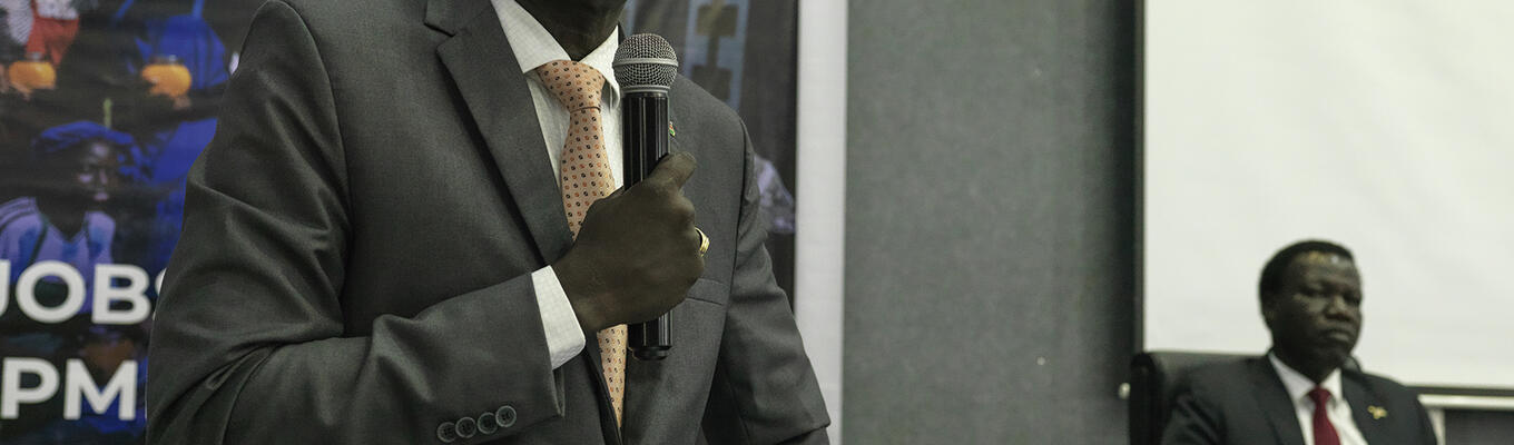 South Sudanese government official speaks into a microphone in conference venue