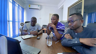 Three Ghanaian man around phone for conference call