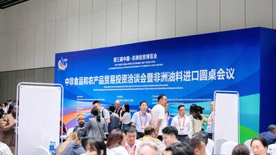 Group of business leaders inside Chinese conference hall beneath blue sign