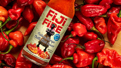 Bottle labelled Fiji Fire rests on a bed of red chilli peppers