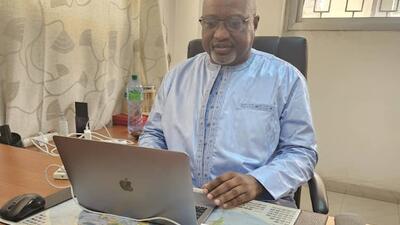 Senegalese man in blue shirt sits at laptop