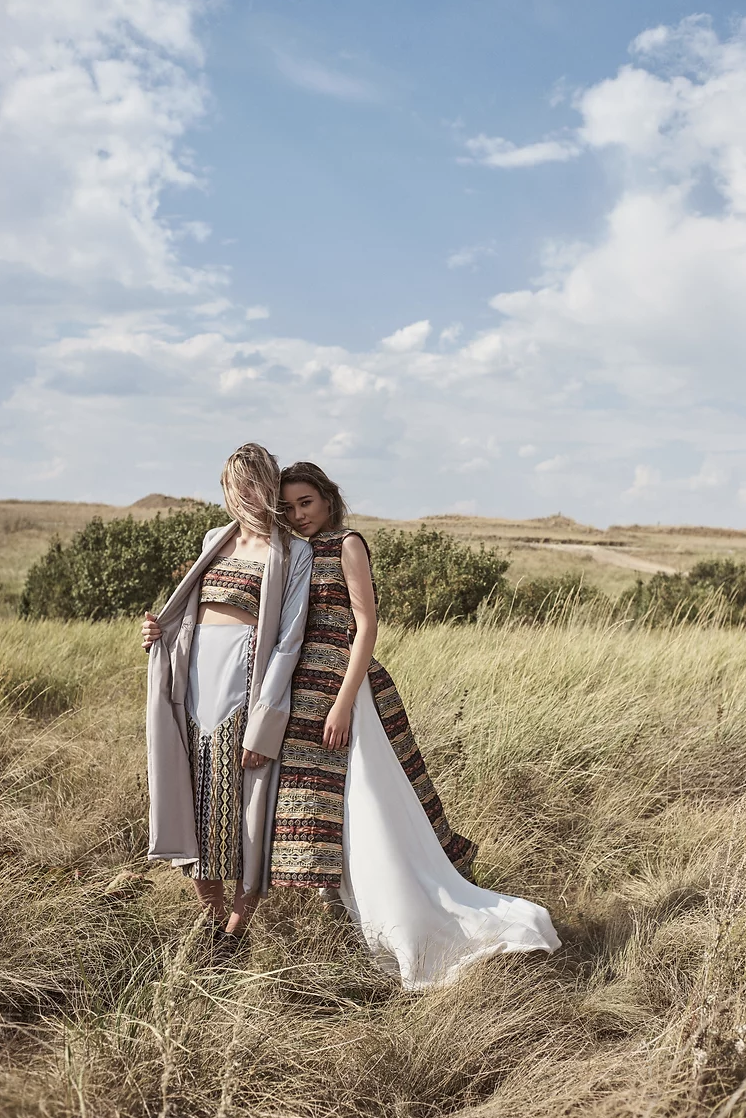 Two female models stand in field wearing Kazakh fashions