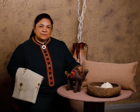 Woman posing with woven items by a table