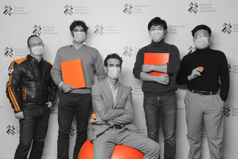 Five men in black and white holding orange items looking serious