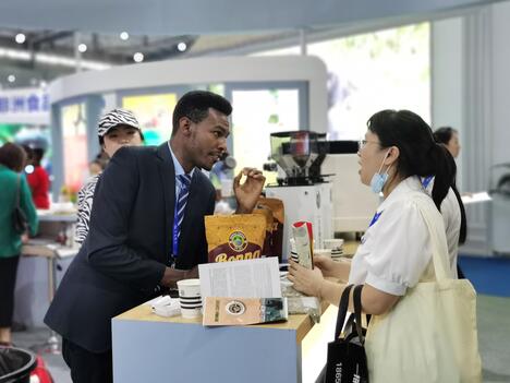 Ethiopian businessman speaks with customer over coffee stand in Chinese expo