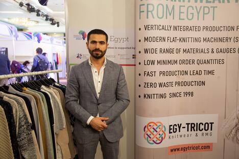 Egyptian businessman in a suit stands next to fashion display at conference centre