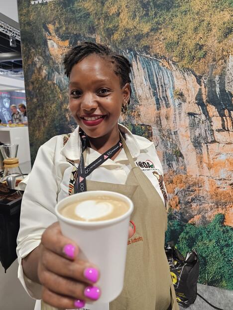 Ugandan coffee promoter holds a cup of coffee at trade fair