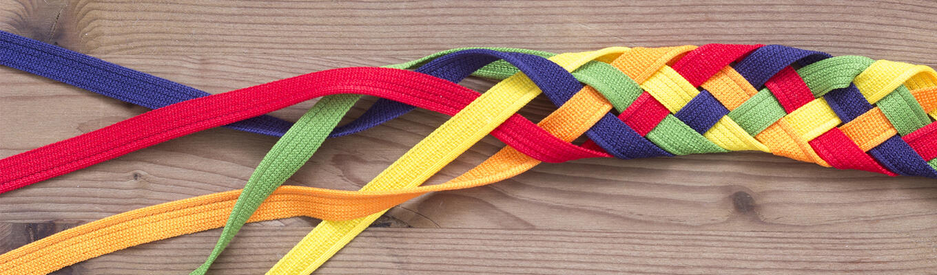Brightly coloured laces woven together, tightly at right of image, and undone towards left of image