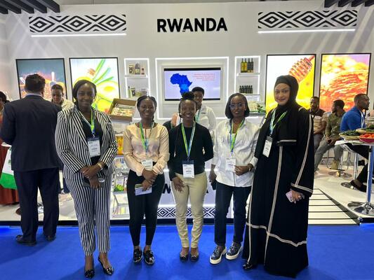Group of five women standing in front of a Rwanda country trade fair booth section. 
