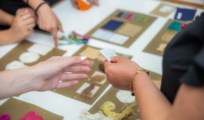 Close-up shot of hands manipulating and experimenting with different types of textiles and fabric materials.