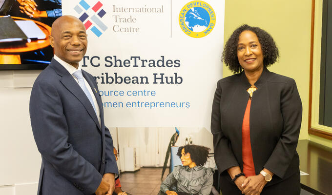 Man and woman in business attire stand next to banner reading ITC SheTrades Hub