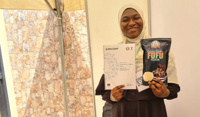 Woman in white headscarf holds brochure and packet of cassava flour