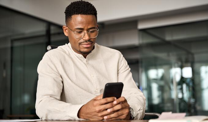 Male entrepreneur sits at desk holding phone