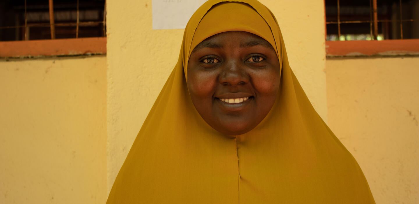 A young refugee wearing a yellow veil smiles