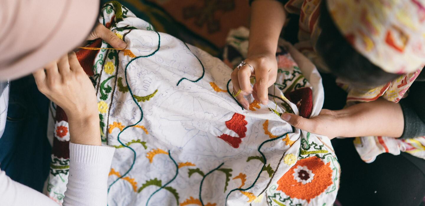 Artisans from the Ozara social enterprise in Khujand, Tajikistan, work on a piece of Suzani embroidery, traditionally used in marriage ceremonies in Tajik culture.