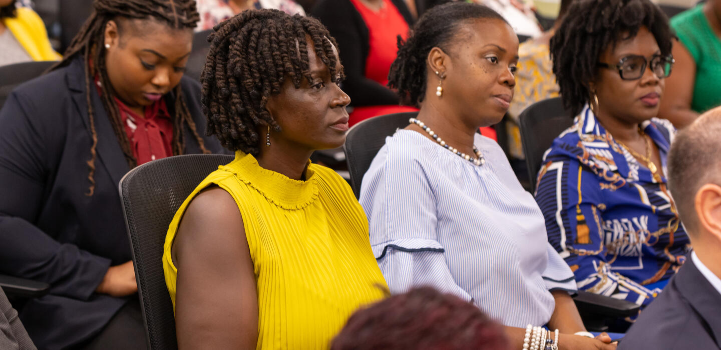 Femmes assises dans le public d'une salle de conférence, attentives aux orateurs