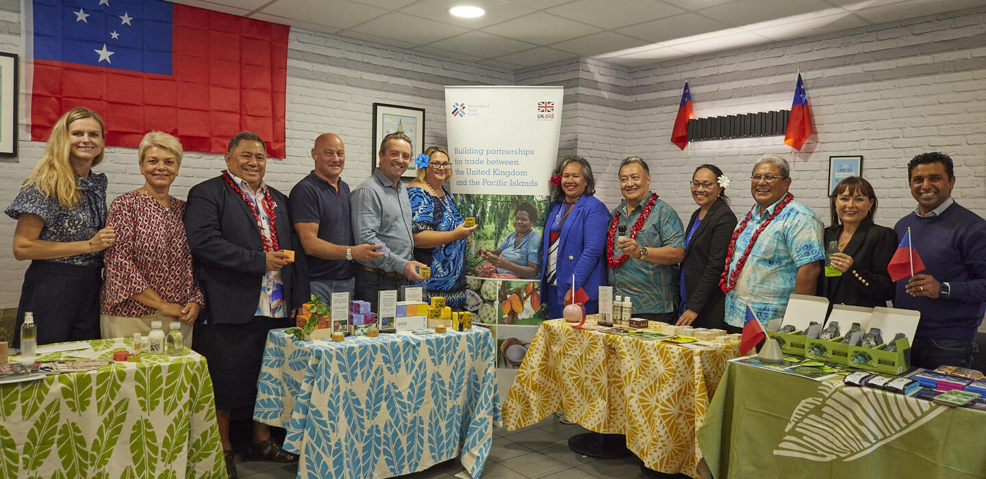 Group of business leaders and diplomats stand by display of Samoan products