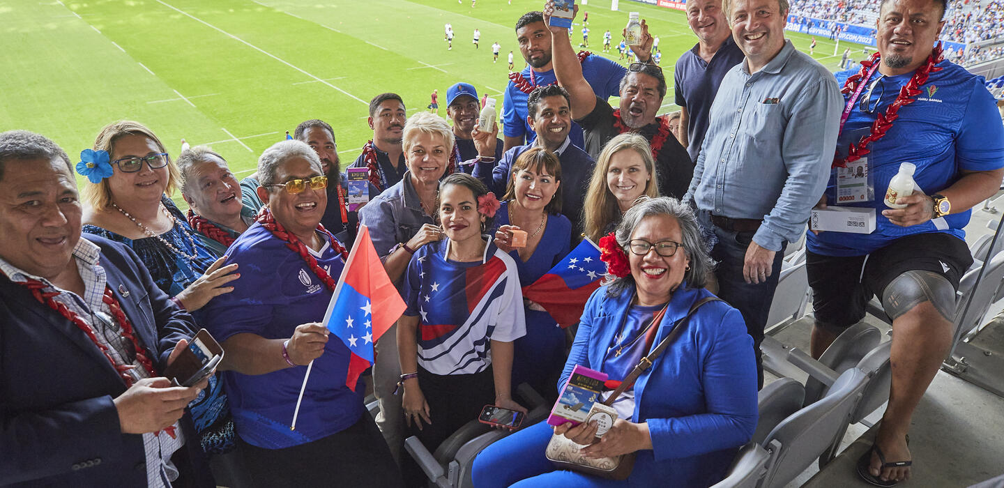 Samoan rugby players, business owners and diplomats pose in rugby stadium
