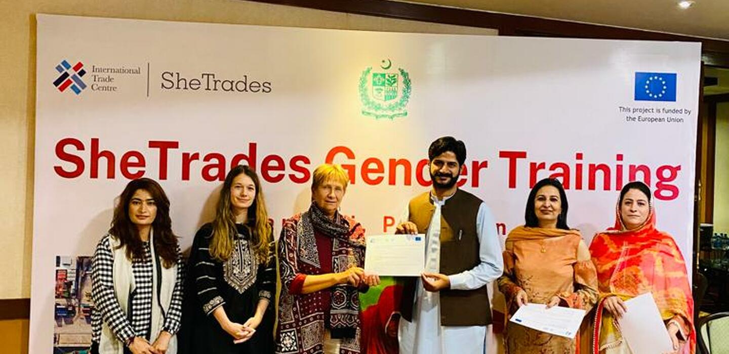Group stands in front of SheTrades banner at workshop in Pakistan