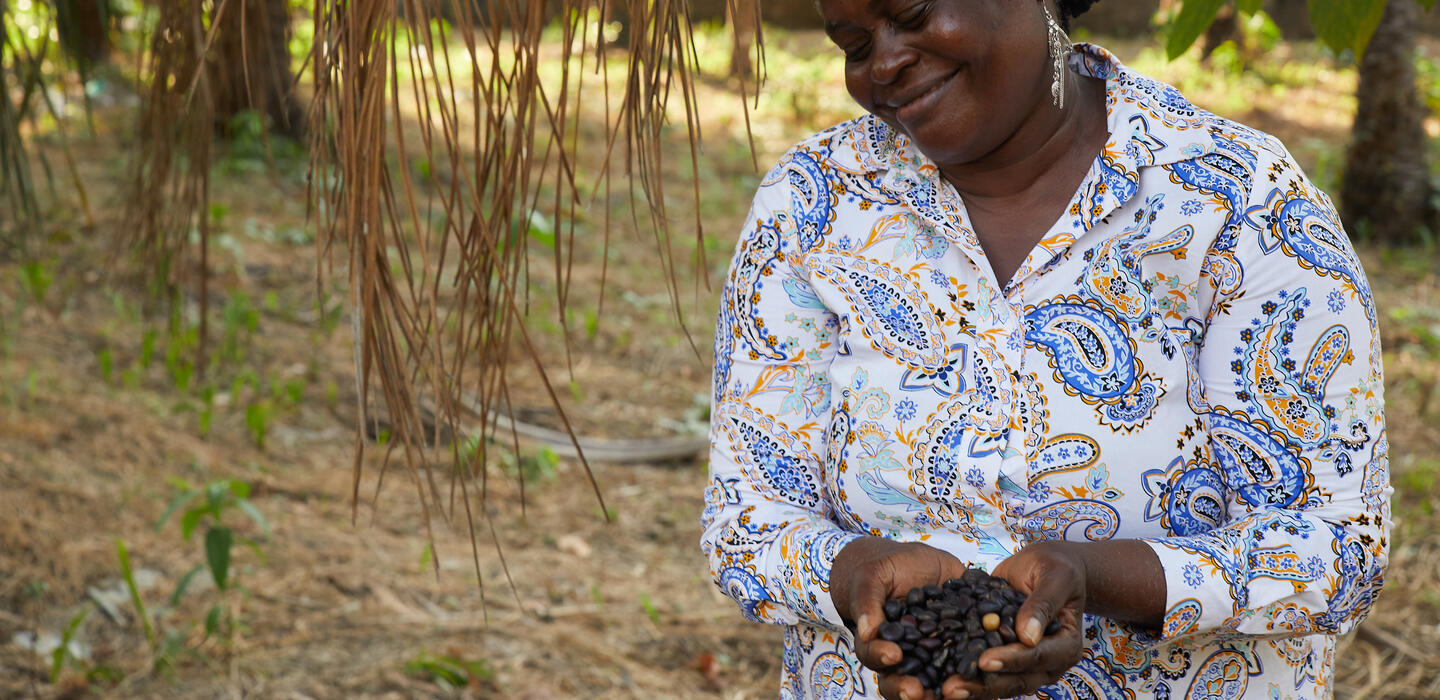 Woman holds palm fruit kernels on plantation