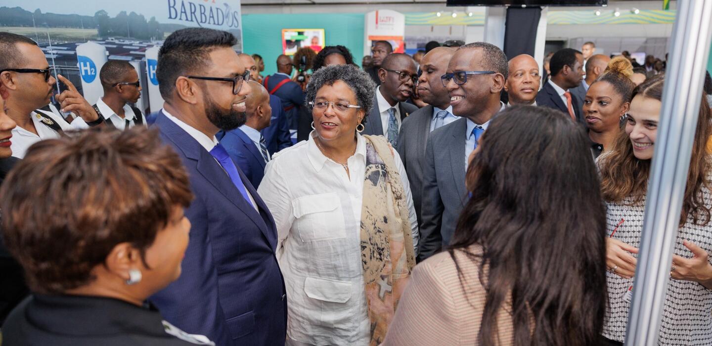 Des chefs d'État discutent de manière informelle devant la bannière d'Invest Barbados.