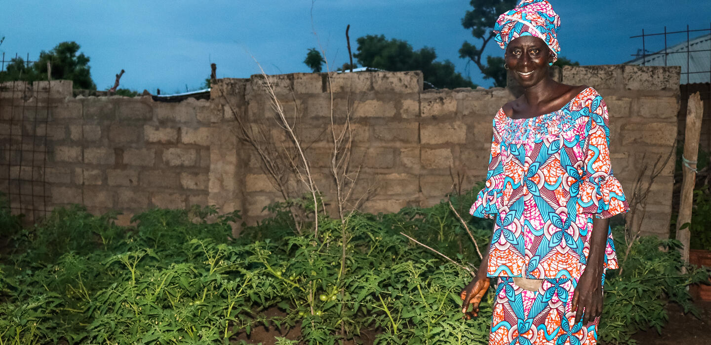 Fatoumata Gassama stands in her field, dressed in a colourful boubou