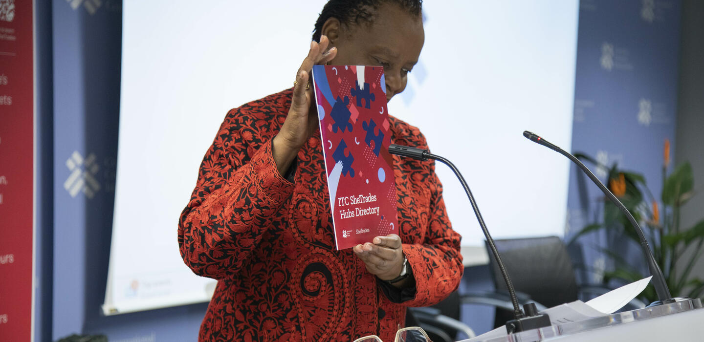 Woman standing behind a podium holding a booklet.