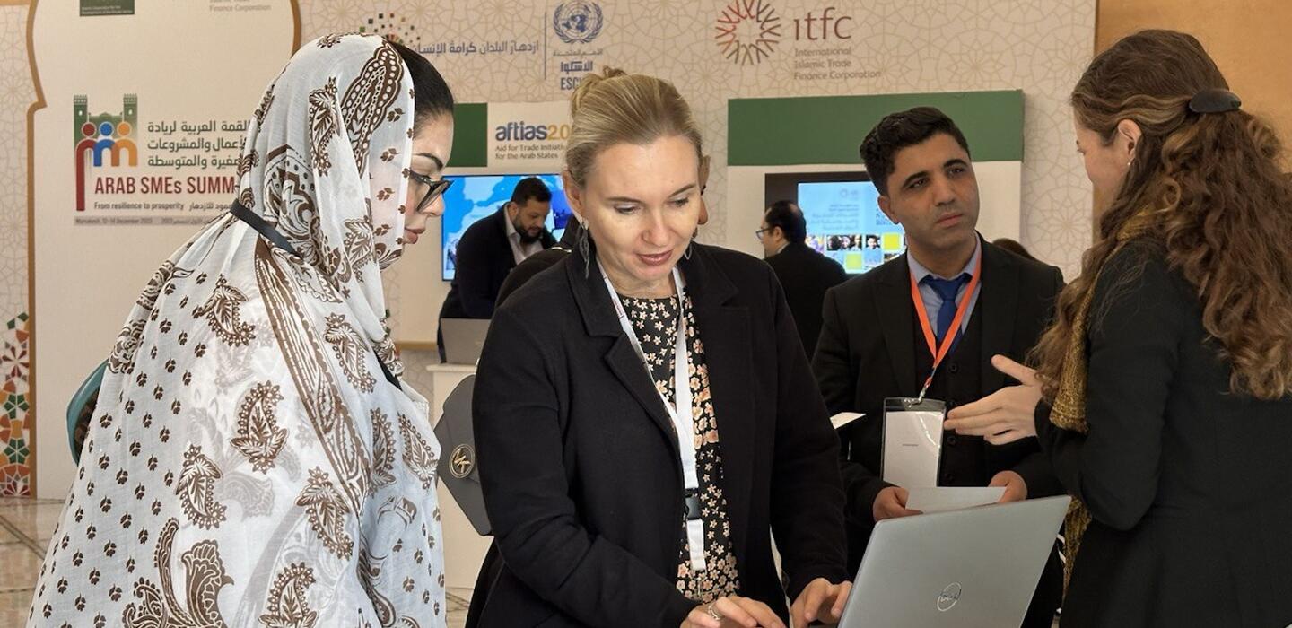 Two women look at laptop screen at ITC booth at trade fair