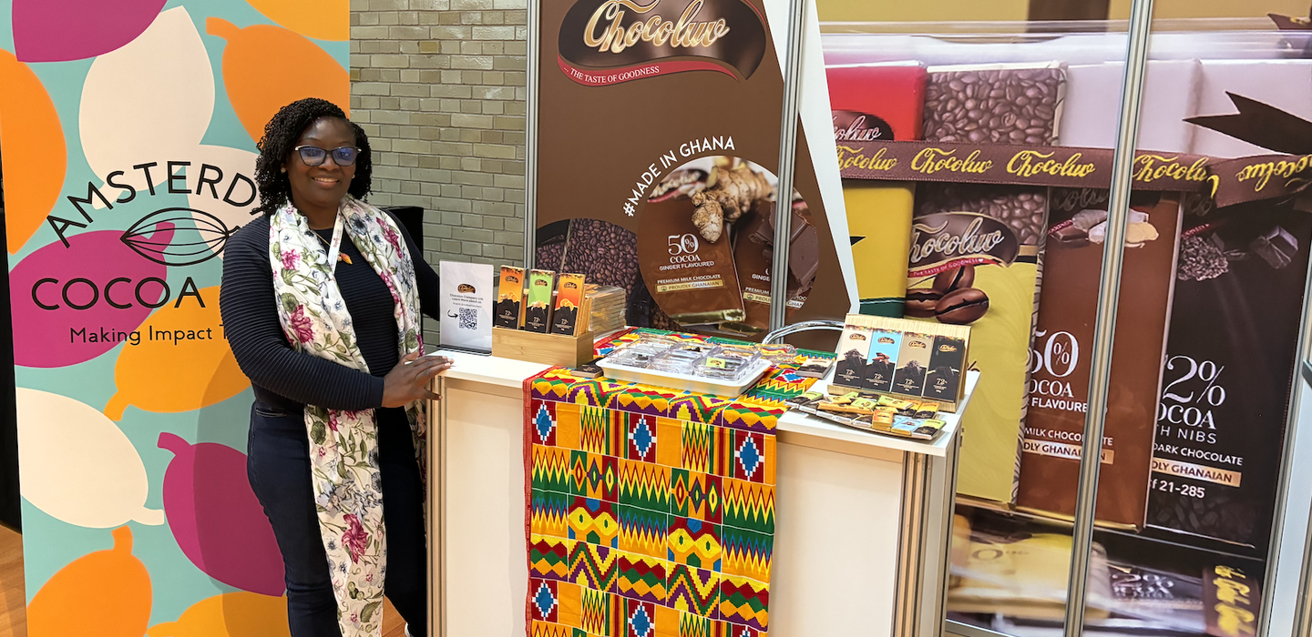 Una mujer ghanesa junto a sus productos de chocolate en una feria comercial.