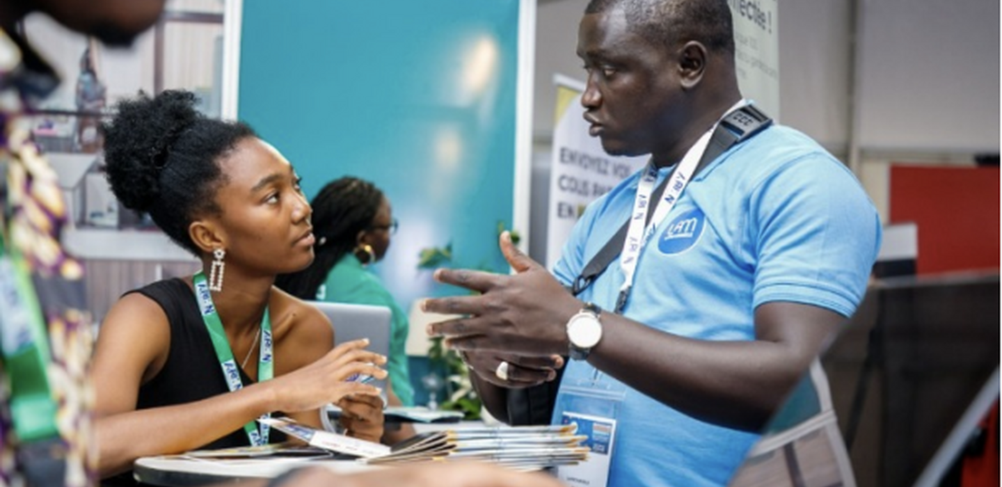 West African tech entrepreneur explains his product to a potential customer at a trade fair