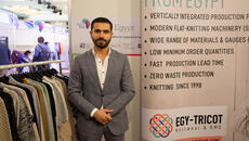 Young Egyptian businessman stands next to display for his textile company