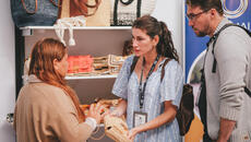 Malagasy fashion designer discusses with two clients at trade show