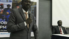 South Sudanese government official speaks into a microphone in conference venue